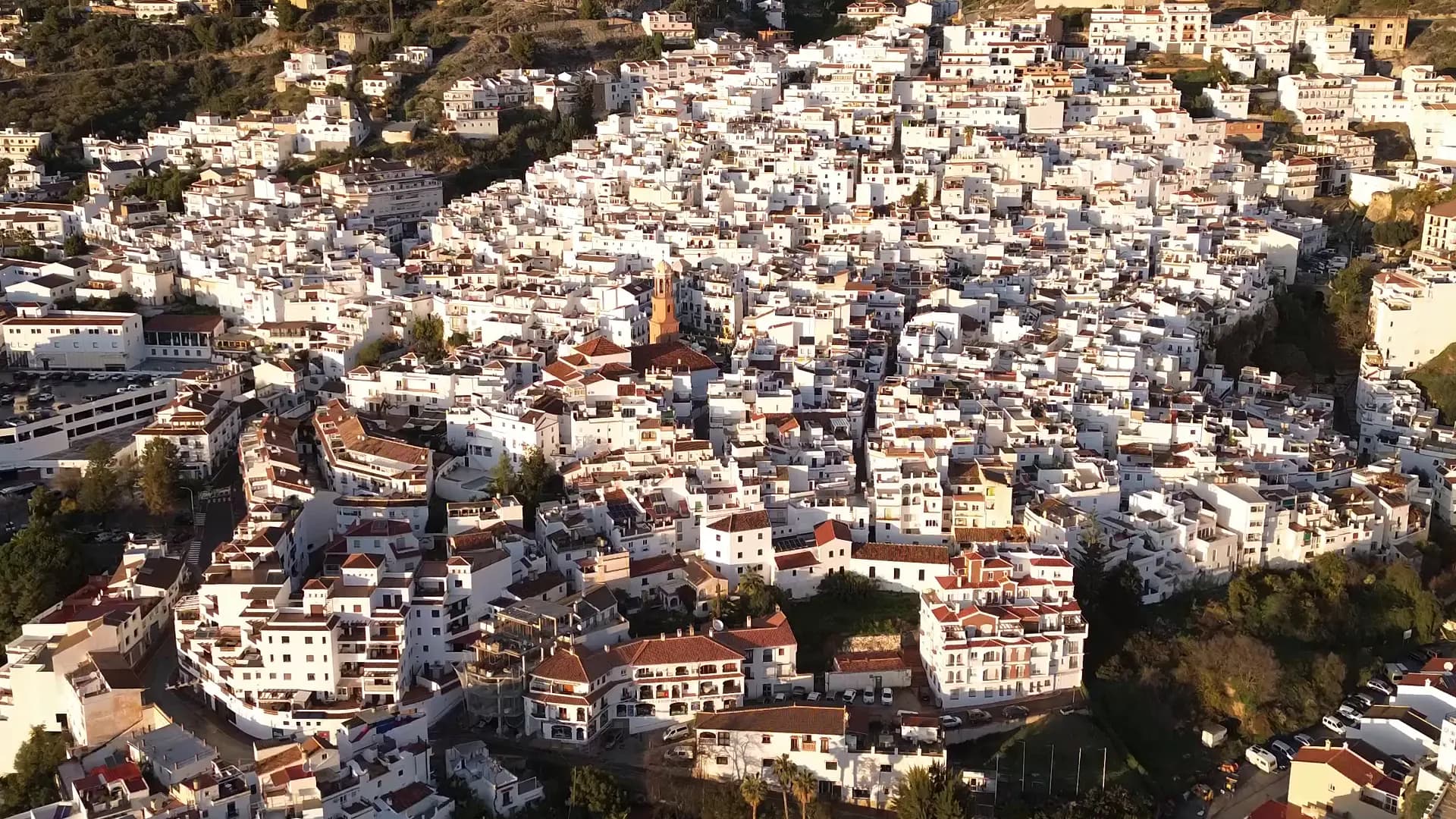Vue panoramique d'un village blanc de l'Axarquía, avec montagnes et végétation méditerranéenne en arrière-plan